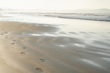 Footprints of bare feet on the sand of the beach. The coast of the ocean, the sea. Tourist background for travel agency. Stock photo