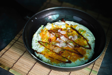 Fried eggs in a pan with sauce, onion, garlic and coriander.Crushed egg, Thai food