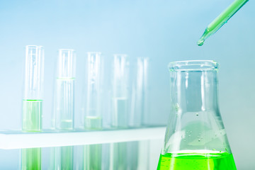 Sample dripping pipettes into Erlenmeyer bottles containing chemical green, background, close