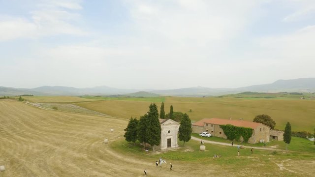 Chiesa Cappella della Madonna di Vitaleta piccola in mezzo a un campo di grano tra i cipressi.