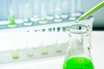 Sample dripping pipettes into Erlenmeyer bottles containing chemical green, background, close