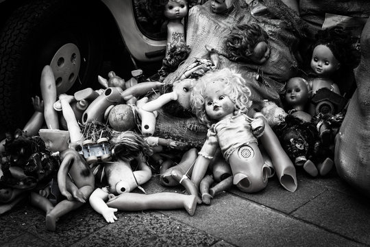 old dolls dumped in a heap at the yellow car, trash of children's toys, background for Halloween