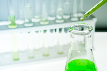 Sample dripping pipettes into Erlenmeyer bottles containing chemical green, background, close