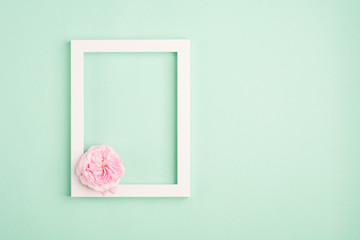 Beautiful rose flowers and blank frame on pastel mint background. Soft light color. Top view, copy space.	
