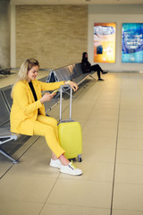 Fototapeta na wymiar Woman traveler looking at smartphone waiting her airport flight check-in