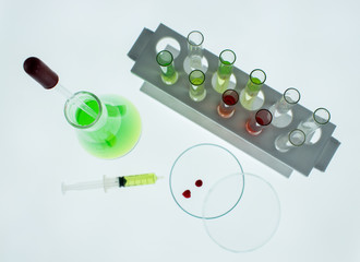 Erlenmeyer flask, Petri dish, Test tubes and a syringe with drops of blood inside is placed on...