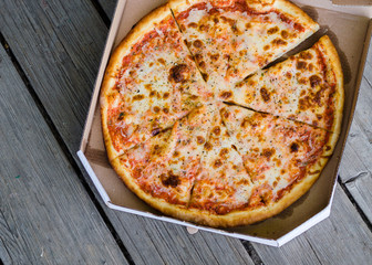pizza in the box on old wooden background. Delivery concept