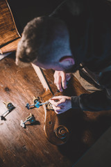 Young luthier working in his workshop, building a double bass
