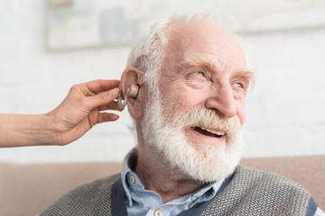 Happy grey haired man with hearing aid, and looking away