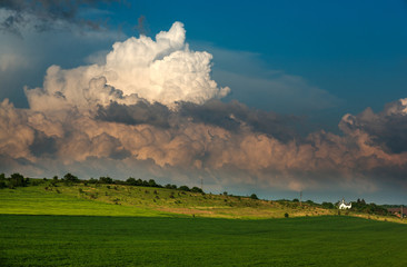 Fototapeta na wymiar Green meadows landscape in countryside hills on impressive huge clouds in sky, beauty in nature
