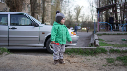 Little boy with toys on the street near car in the city