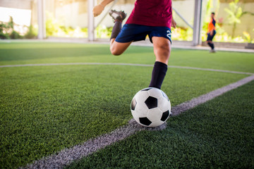 Soccer player speed run to shoot ball to goal on artificial turf.