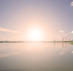 Fototapeta premium Sunset over the lake and the city.