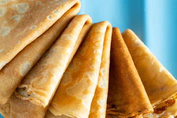 fresh baked thin pancake on blue background. food and baking