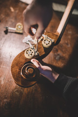 hands of artisan luthier varnishing, building a double bass