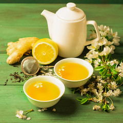 Tea lemon ginger with honey in a white cup and a teapot on a wooden rustic background. Healthy drink for detox health.