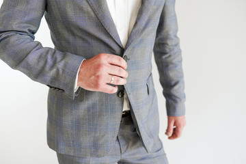 the groom with wedding ring in a grey suit on white background