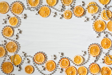 Christmas composition with dried oranges, white stars and silver bead chain - white background with deep shadows