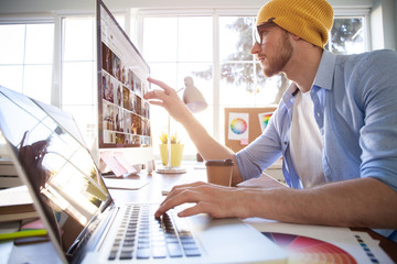 Young creative manager sitting at his table and working on computer