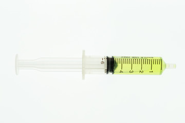 Syringe containing a green substance inside is placed on a white background.Science experiment equipment.