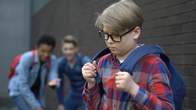 Evil teenagers laughing at new boy in school, calling names, verbal bullying