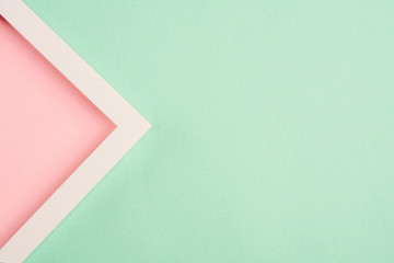 Pink triangle in a frame on a green background. Top view. Copy space