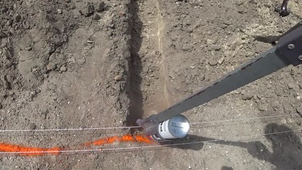 Engineer builder markings with orange paint on a construction site on the ground. Drawing marking lines with paint from bolonchik on sand. Ramite where you need to dig a trench for pipes or foundation