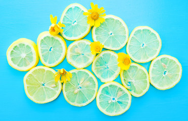 Bright food concept with yellow lemon slices and flowers on blue background for horizontal banner.