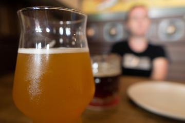 Mug of cold beer with misted glass.  Girl in blur on background.