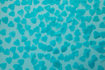 Paper blue confetti in the form of hearts on a dark blue background. Holiday concept.