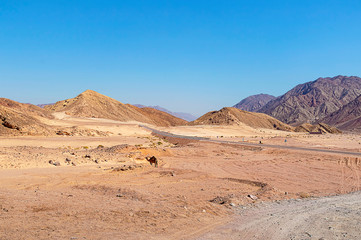 Fototapeta na wymiar desert-mountainous terrain, asphalt road with fences and road