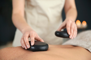 Fototapeta premium Man man receiving hot stone massage in spa salon, closeup