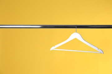 Metal rack with clothes hanger on color background, space for text