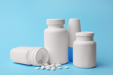 Containers and scattered pills on color background