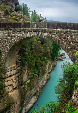 Woman looking at the sky on the ancient bridge. Koprulu Canyon in Manavgat, Antalya, Turkey. Amazing river landscape. Travel, tourism and holiday concept