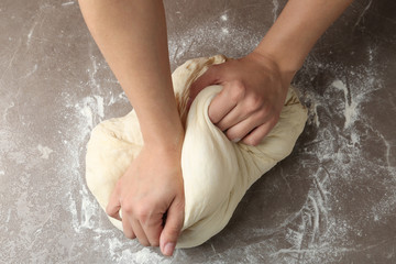 Female baker preparing bread dough at grey table, top view