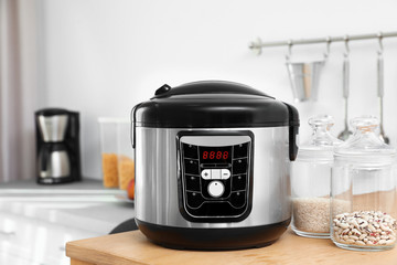 Jars with rice and beans near modern multi cooker on table in kitchen