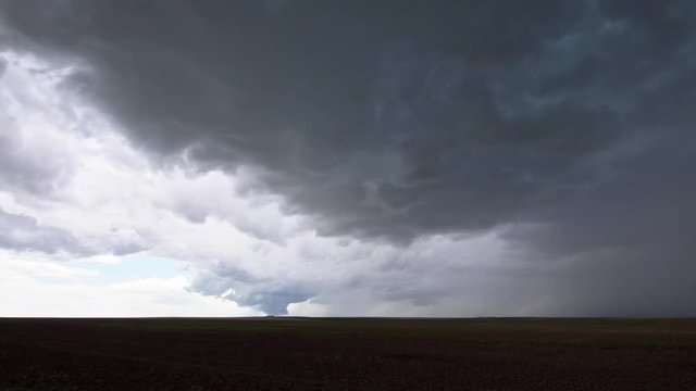 Wide view of storm as tornado quickly touches down in the distance in field in the Colorado plains.