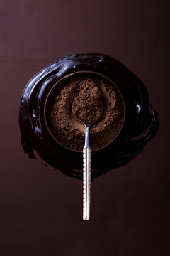 Cocoa or cacao  powder in bowl, on chocolate dipper, top view close up