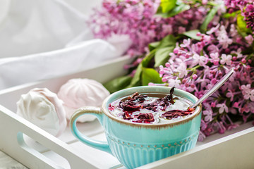The tea to a karkada served in a gift box with marshmallows and a bouquet of a lilac. Close up.