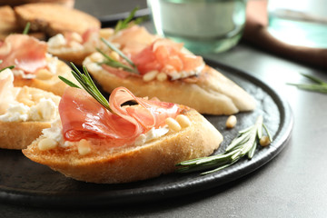 Tasty bruschettas with prosciutto and cream cheese served on table, closeup. Space for text