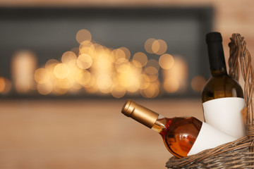 Wicker basket with bottles of wine against blurred background, closeup. Space for text