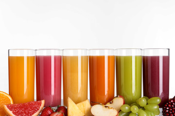 Glasses with different juices and fresh fruits on white background