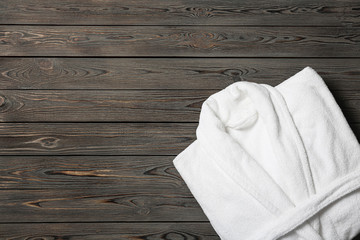 Clean folded bathrobe on wooden background, top view. Space for text - obrazy, fototapety, plakaty