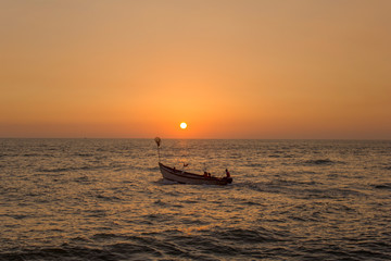 young family with children in a large pleasure boat with a motor in the ocean against the bright orange yellow sky of sunset and sun