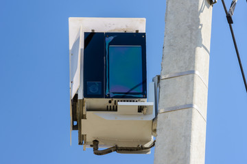 Speed camera car for surveillance on highway, tool of police for control road traffic. Speed radar cameras mounted on concrete pole against a clear blue sky. Speed control.