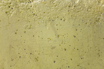 old dirty porous yellow concrete wall with holes of various shapes and sizes. rough surface texture