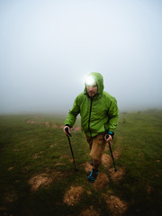 Young man with headlamp hiking through the fog © Eneko Aldaz