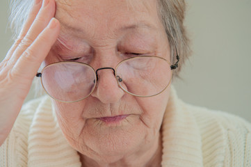 Elderly woman with beautiful wrinkled face is holding pills in her hands to choose medicines. Selective focus depth of field