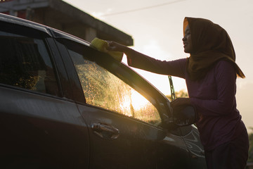 hijab Woman car washing with yellow sponge  washing her car  in front of the house